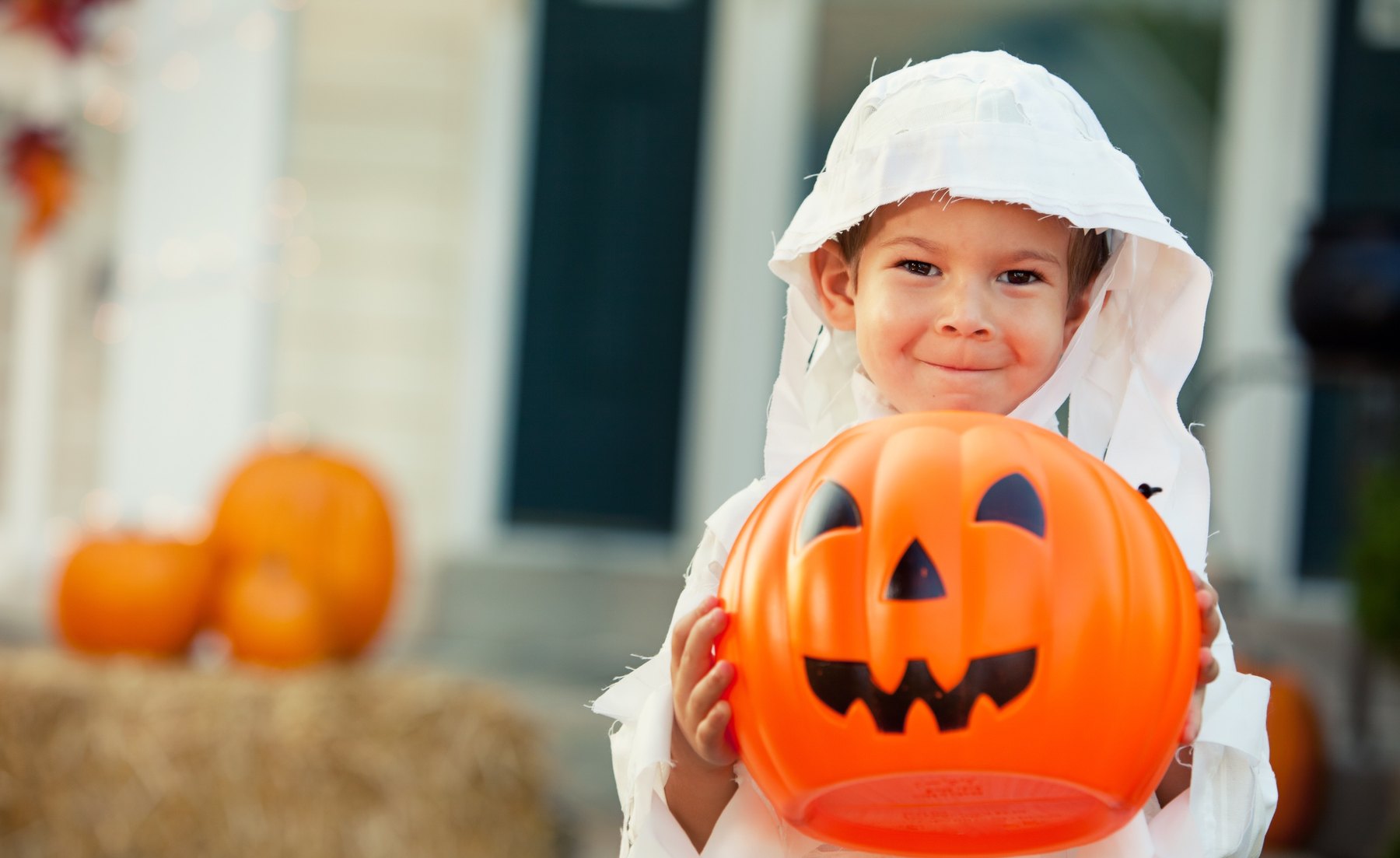 A child in a costume holding a jack-o'-lantern trick-or-treat pail